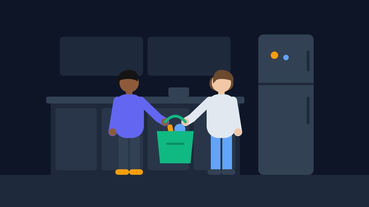 A couple carries one heavy grocery bag between them into the kitchen